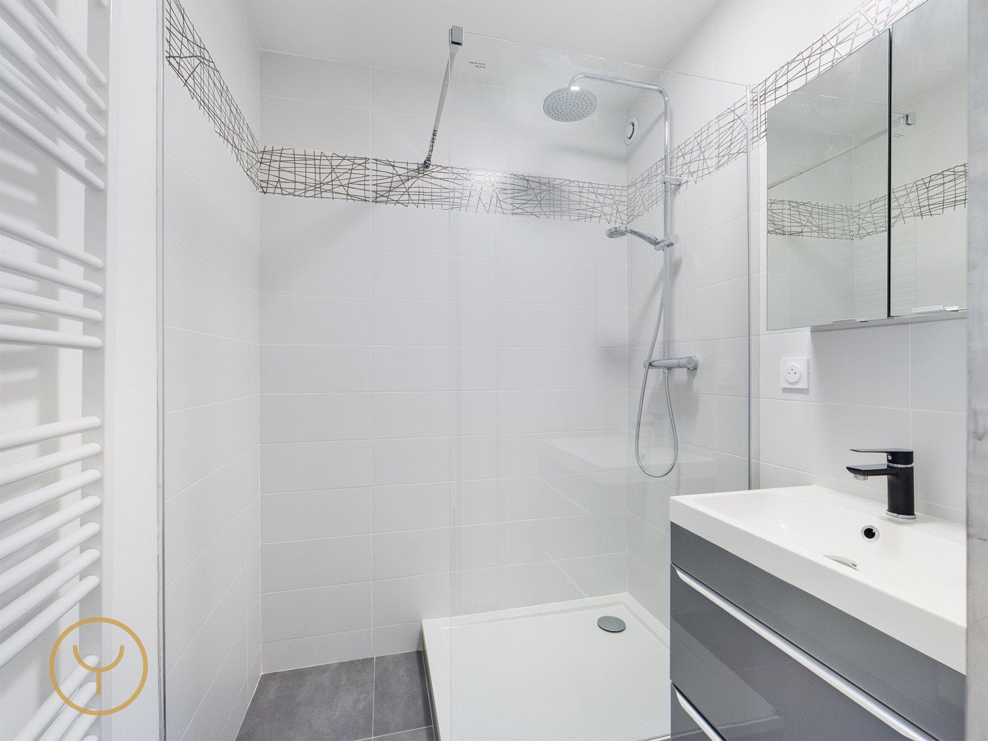 Salle de bain rénovée avec douche et meuble vasque